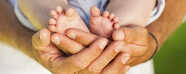 Image of hands holding baby's feet.  Our hands enable us to nurture others (Sandhurst Hand Therapy Bendigo)